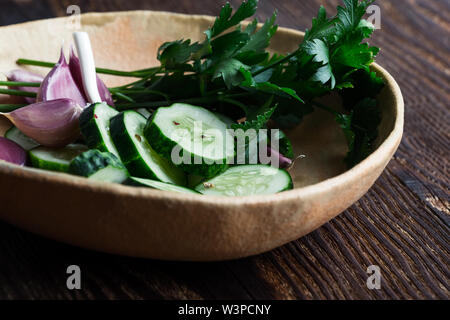 Bol de concombres biologiques fraîchement cueillies et l'ail, une salade fraîche avec des légumes et le persil sur table rustique à base de plantes, nourriture, Close up, s Banque D'Images