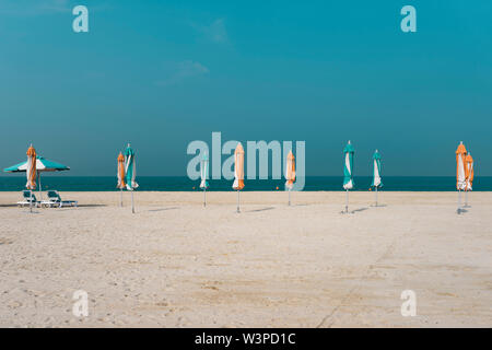 Plage de sable avec parasols fermés sur la toile de fond de l'eau d'azur Banque D'Images