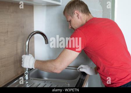 La réparation et la décoration. plumber repairing des conduites d'eau dans la cuisine sous l'évier Banque D'Images