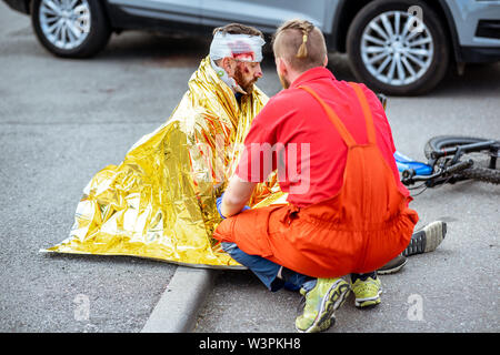 Ambluence couverture travailleur homme blessé avec une couverture thermique, fournissant des soins d'urgence après l'accident de la route Banque D'Images