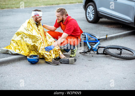 Ambluence couverture travailleur homme blessé avec une couverture thermique, fournissant des soins d'urgence après l'accident de la route Banque D'Images