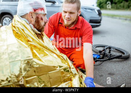 Ambluence couverture travailleur homme blessé avec une couverture thermique, fournissant des soins d'urgence après l'accident de la route Banque D'Images