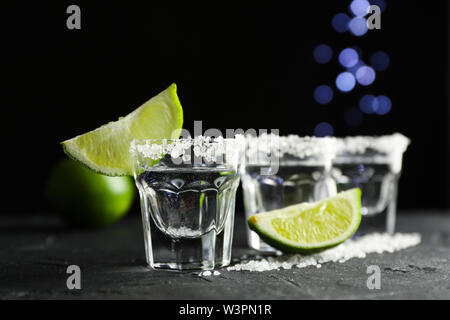 Tequila shots avec sel et lime slices sur fond noir Banque D'Images