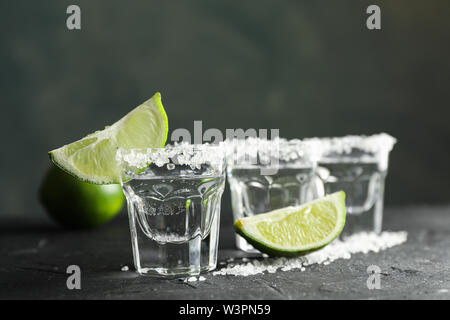Tequila shots avec sel et lime slices sur fond noir Banque D'Images