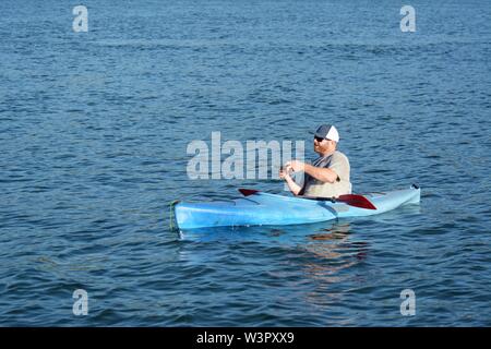 Un vrai pêcheur heureux avec pris petit bass sur son kayak bleu sur le lac Clear Clearlake California USA Amérique le calme journée ensoleillée en été par lui-même Banque D'Images