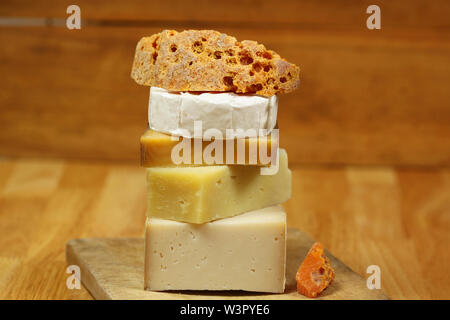 Pile de différentes sortes de fromage sur planche de bois - fromage de chèvre, camembert et mimolette Banque D'Images