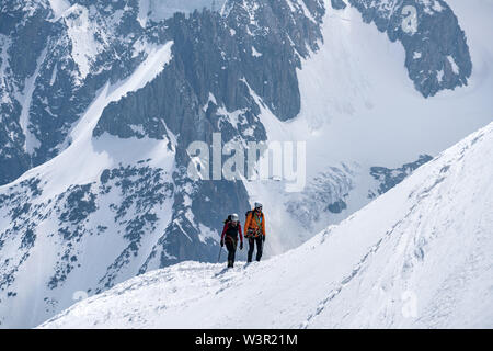 Chamonix, France - 18/06/2019 L'alpiniste : on snowy ridge contre l'énorme montagne l'arrière-plan. Banque D'Images