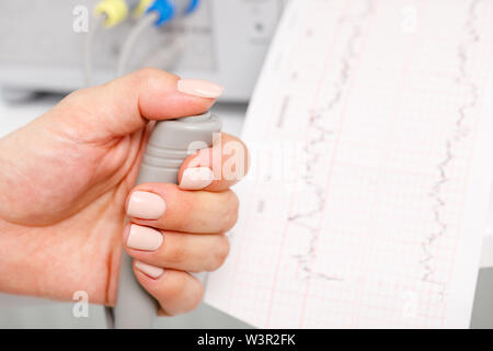 Close-up shot of pregnant woman's hand holding contrôleur de l'Cardiotocograph alias machine de monitorage électronique du foetus (EFM) enregistrement de la fetal heartb Banque D'Images