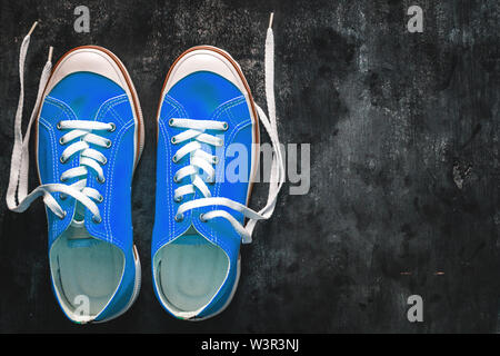 Cyan bleu-vert-turquoise chaussures avec lacets déliée sur un fond en béton foncé. Copier l'espace. Vue de dessus Banque D'Images