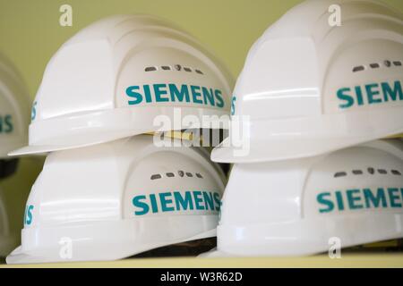 15 juillet 2019, Saxe, Görlitz : Blanc casques de protection avec la mention 'Siemens' sont sur une étagère dans un hall d'assemblage de l'usine de turbine Siemens. Photo : Sebastian Kahnert/dpa-Zentralbild/dpa Banque D'Images