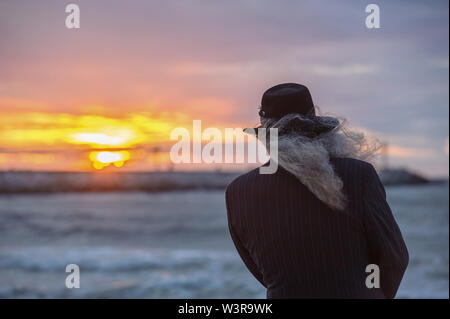 Vieil homme regardant vers le soleil sur la mer Banque D'Images