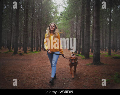 Jeune femme blonde marcher avec son chien dans la forêt Banque D'Images