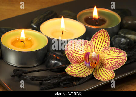 Trois bougies allumées et orchidée, fleur avec les gousses de vanille. Traitement spa aromatique Banque D'Images