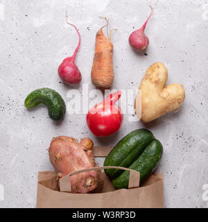 Ugly mûrs légumes dispersés hors de sac de papier sur fond de béton gris. Banque D'Images