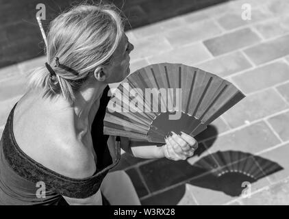 Belle caucasian woman utilise un ventilateur à main pour vous rafraîchir par une chaude journée d'été Banque D'Images