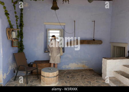 Une femme regarde à travers une fenêtre à Profitis Ilias (prophète Ilias) monastère dans l'île d'Hydra, Grèce. Banque D'Images