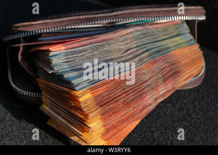 Une vue rapprochée de pile de deux cents, cent cinquante rand sound notes africaines qui sort de l'avant d'un portefeuille en cuir brun sur un ba isolés Banque D'Images