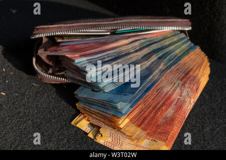 Une vue rapprochée de pile de deux cents, cent cinquante rand sound notes africaines qui sort de l'avant d'un portefeuille en cuir brun sur un ba isolés Banque D'Images