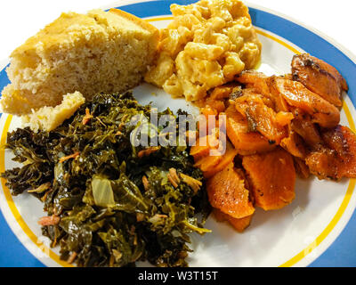Une plaque de southern comfort food en Amérique. Une portion de greens kale, confit d'ignames, des macaronis au fromage et cornbread. Banque D'Images