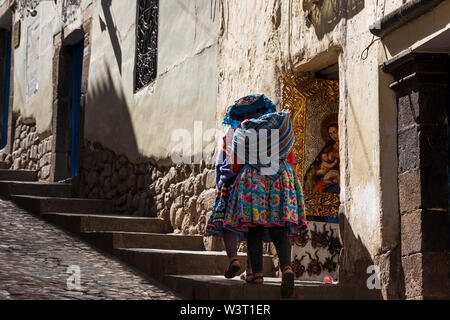 Les femmes en robe traditionnelle péruvienne marches sur la rue Hatunrumiyoc, Cusco, Pérou, Amérique du Sud Banque D'Images