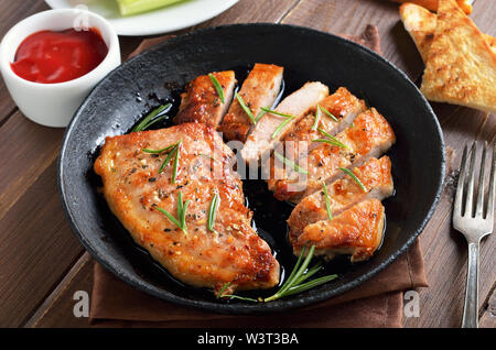 Steaks de porc dans une poêle à frire, la sauce tomate sur la table en bois Banque D'Images