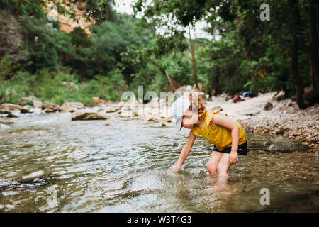 Jeune fille en mettant la main dans l'eau à Barton Springs sur une chaude journée d'été Banque D'Images