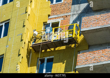 Travail à haute altitude sur les murs extérieurs de l'isolation en laine de verre et de plâtre Banque D'Images