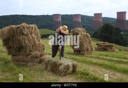 Agriculteur empilant des balles de foin à la main en Grande-Bretagne Banque D'Images