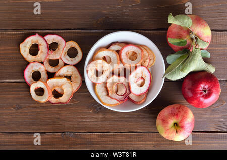 Anneaux de pommes séchées dans un bol blanc sur une table de bois et des pommes fraîches. Haut de la vue, télévision lay Banque D'Images