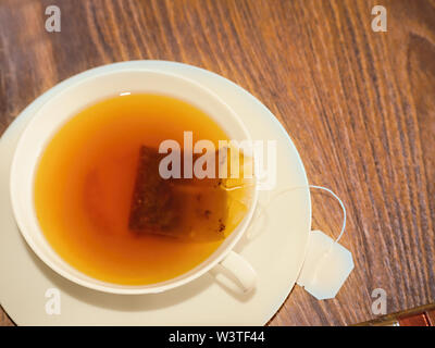 Un livre blanc avec une délicate tasse de thé noir fraîchement moulu. Le sachet de thé est encore dans la tasse. Close-up Banque D'Images