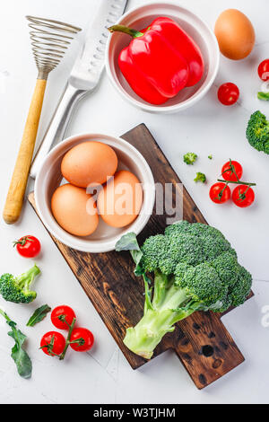 Ingrédients pour la cuisson des oeufs Frittata aux légumes frais et - le brocoli, poivrons, tomates cerise sur un fond clair. Vue de dessus Banque D'Images