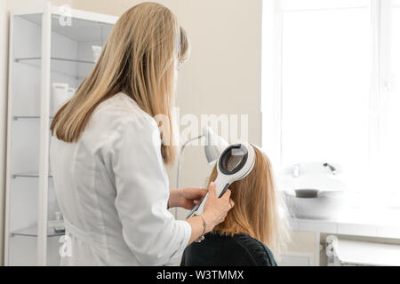 Le médecin dermatologue trichologist examine le cuir chevelu et les cheveux du patient état avec un dermatoscope. Banque D'Images