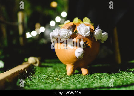 Une tirelire en terre cuite, décoré avec des fleurs, et peint avec sympathie et curieusement. Banque D'Images