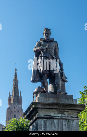 Bruges, Flandre occidentale, Belgique - 17 juin 2019 : Simon Stevin statue avec flèche de OLV Cathédrale en arrière sous ciel bleu. Feuillage vert certains. Pigeon sur son Banque D'Images