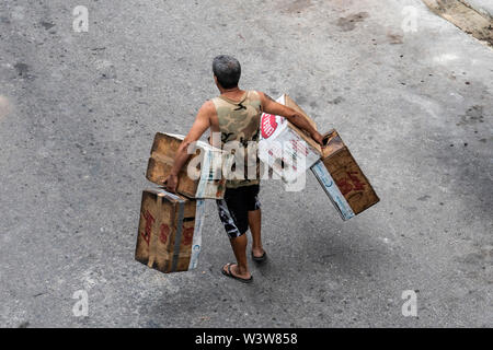 Un homme portant des caisses et cartons marche le long de la rue à La Havane, Cuba Banque D'Images