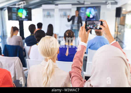 Close-up of female executive en cliquant sur photo de séminaire d'entreprise avec un téléphone mobile Banque D'Images