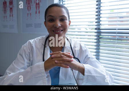 Femme médecin assis avec les mains jointes dans l'hôpital Banque D'Images