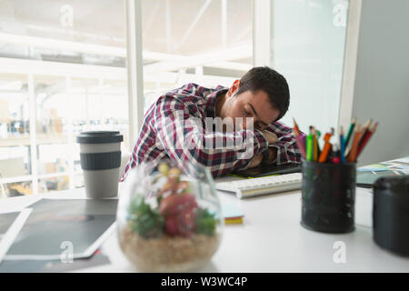 Graphiste mâle dormir sur desk in office Banque D'Images