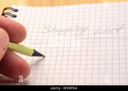 Un homme écrit au crayon jaune sur un ordinateur portable. Inscription Liste d'achat. Vue d'en haut Banque D'Images