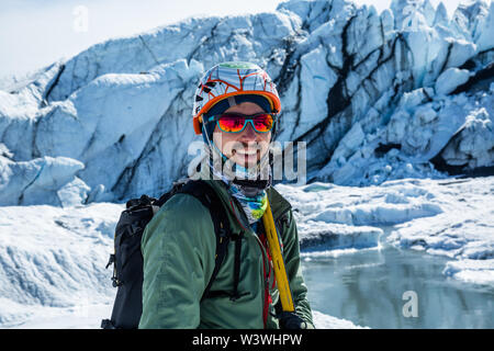 Guide de l'escalade sur glace professionnel avec casque et piolet, l'article ci-dessous de la cascade de la Matanuska Glacier en Alaska. Banque D'Images