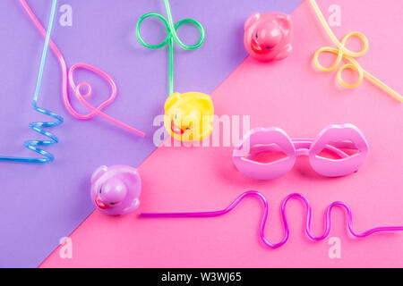 Funky coloré de l'été mise à plat avec les articles drôle - pailles, de canards en caoutchouc, lunettes de forme de lèvre. Rose et violet fond duotone. Banque D'Images