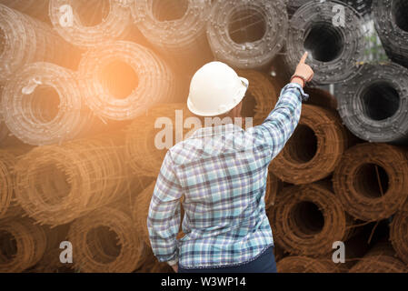 Ingénieur femme porter chemise bleue et le casque blanc sur un arrière-plan industriel. Banque D'Images