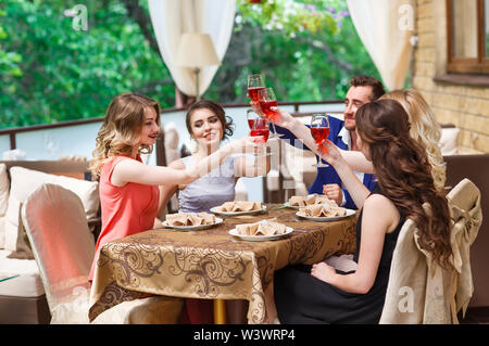 Les amis de boire du vin sur la terrasse en été. Banque D'Images