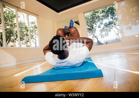 Vue arrière de young African American man doing sit-up de l'exercice dans la salle de sport. Remise en forme de la scène de sexe masculin modèle crunch Banque D'Images