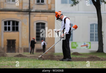 16 juillet 2019, Saxe, Wermsdorf : Un assistant de l'artiste action Witthaus tond les lignes de l'ancien jardin baroque dans les prés dans le parc du château de Hubertusburg. Le plus grand pavillon de chasse a retourné une fraction de son jardin perdu. Avec environ 40 bénévoles, l'action de Cologne artiste a cut gratuitement quelques-unes des formes de bijoux dans l'ancien parc depuis le 1er juillet. Sur 10 000 mètres carrés, l'axe central et le centre du jardin baroque composition ont été ressuscités - un dixième de l'ancien complexe. Mais les visiteurs à l'axone 'Versailles' faut se dépêcher, parce que c'est Banque D'Images