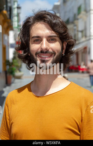 Portraits d'un jeune homme dans la rue, à la caméra à tout sourire avec un t-shirt orange Banque D'Images