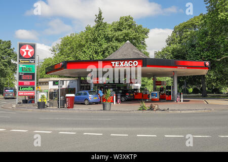 Garage station service Texaco montrant l'essence et les prix du carburant diesel avec jeune femme de remplir sa voiture Banque D'Images