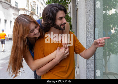 Portraits d'un couple de jeunes, complices et souriant à la boutique à Windows Banque D'Images