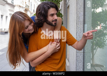 Portraits d'un couple de jeunes, complices et souriant à la boutique à Windows Banque D'Images