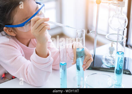 Enfant asiatique et fiole chimiste holding test tube dans les mains dans l'expérience de la chimie de l'apprentissage de laboratoire. La chimie et les sciences de l'éducation scientifique concept. Les enfants Banque D'Images